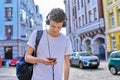 Student teenager in headphones with backpack looks into the smartphone screen Royalty Free Stock Photo