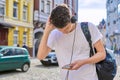 Student teenager in headphones with backpack looks into the smartphone screen Royalty Free Stock Photo