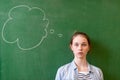 Student thinking blackboard concept. Pensive girl looking at thought bubble on chalkboard background. Caucasian student. Royalty Free Stock Photo