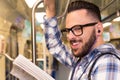 Student traveler with glasses reading book while riding to school by subway train. Concept of commute, effort, aspirations.