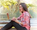 Student using laptop on park bench Royalty Free Stock Photo
