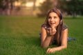 Student using voice recognition with a smart phone to record notes sitting on the grass in a park with headphones on head Royalty Free Stock Photo