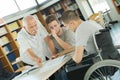 Student in wheelchair talking with classmate and teacher in library Royalty Free Stock Photo