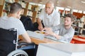 student in wheelchair talking with classmate and teacher in library Royalty Free Stock Photo