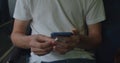 Student in white t-shirt using a mobile phone. Anonymous, no face. Royalty Free Stock Photo