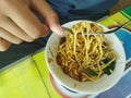 a student who is eating noodles bought in the canteen