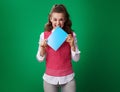 Student woman biting blue notebook isolated on green background Royalty Free Stock Photo