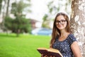 Student woman in glasses holding a book, looking at you smiling Royalty Free Stock Photo