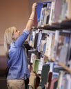 Student woman, library and search bookshelf for studying, learning and scholarship with development at campus. Girl Royalty Free Stock Photo