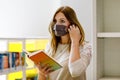 Student woman with medical mask in public university library, choosing books for leisure or education. Woman making