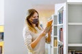 Student woman with medical mask in public university library, choosing books for leisure or education. Woman making