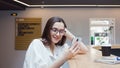 Student girl is sitting at a table and using an app on her smartphone.