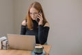 student working remotely. a young woman in a black blouse works on a laptop, talking on the phone and drinking coffee in a cafe. Royalty Free Stock Photo