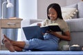 Student, writing and black woman with book in home living room for elearning, studying and knowledge. Laptop, education Royalty Free Stock Photo
