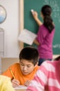 Student writing in notebook in school classroom