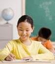 Student writing in notebook in school classroom