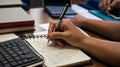 Student Writing in Notebook with Textbooks and Laptop, Representing Academic Dedication Royalty Free Stock Photo