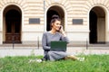 Student young woman is talking by smartphone on grass near university building Royalty Free Stock Photo