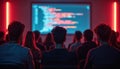 Students attend coding lecture in dark room with red neon lights. Large projector screen displays programming code. Focus on Royalty Free Stock Photo