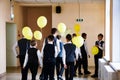 students with balloons in school uniform walk down the corridor