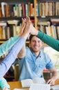 Students with books making high five in library Royalty Free Stock Photo