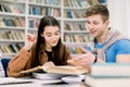 Students, Caucasian handsome boy and pretty girl, sitting at a table in a library while reading books and learning Royalty Free Stock Photo