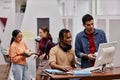 Students in college library focus on two young men using computer