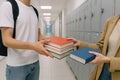 Students exchanging textbooks in school hallway with lockers in background. concept of academic resource sharing, education Royalty Free Stock Photo