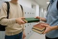 Students exchanging textbooks in school hallway with lockers in background highlighting concepts of academic collaboration and Royalty Free Stock Photo