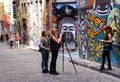 Students filming interview in front of graffiti art