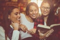 Students girls in library reading book and having conve