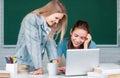 Students girls looking at laptop computer in classroom at school college. Two students doing homework together and Royalty Free Stock Photo