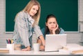 Students girls looking at laptop computer in classroom at school college or university. Two students doing homework Royalty Free Stock Photo