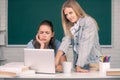 Students girls looking at laptop computer in classroom at school college or university. Two students doing homework Royalty Free Stock Photo