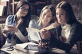 Students girls reading book together in cafe. Royalty Free Stock Photo