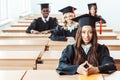 group of multiethnic students in graduation costumes sitting Royalty Free Stock Photo
