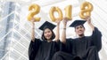 Students in graduation suit sit and gold number balloons 2018