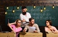 Students, group mates speaking, asking for advice or cheating while teacher watching them. Bearded teacher, lecturer Royalty Free Stock Photo