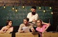 Students, group mates speaking, asking for advice or cheating while teacher watching them. Bearded teacher, lecturer Royalty Free Stock Photo