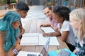 Students, group and reading outdoor at university with books, listening and learning for education on campus. Friends Royalty Free Stock Photo