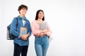 Students holding backpack, laptop and notepads looking on white background