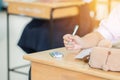 Students holding pen in hands taking exams, writing examination room with undergraduate students inside. Student sitting learning Royalty Free Stock Photo