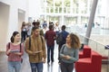 Students holding tablets and phone talk in university lobby Royalty Free Stock Photo