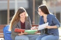 Students learning comparing notes on a bench