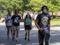 Students, one wearing a protective face mask, walking on a university campus