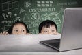 Students peeking laptop with scribble on chalkboard Royalty Free Stock Photo