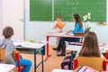 Students read a woman teacher at the blackboard