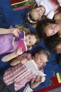 Students Reading Books While Lying On Carpet Royalty Free Stock Photo