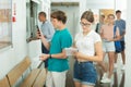 Students record and photograph class schedules in college lobby