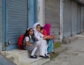 Students sit and wait for the bus to school in Srinagar, India